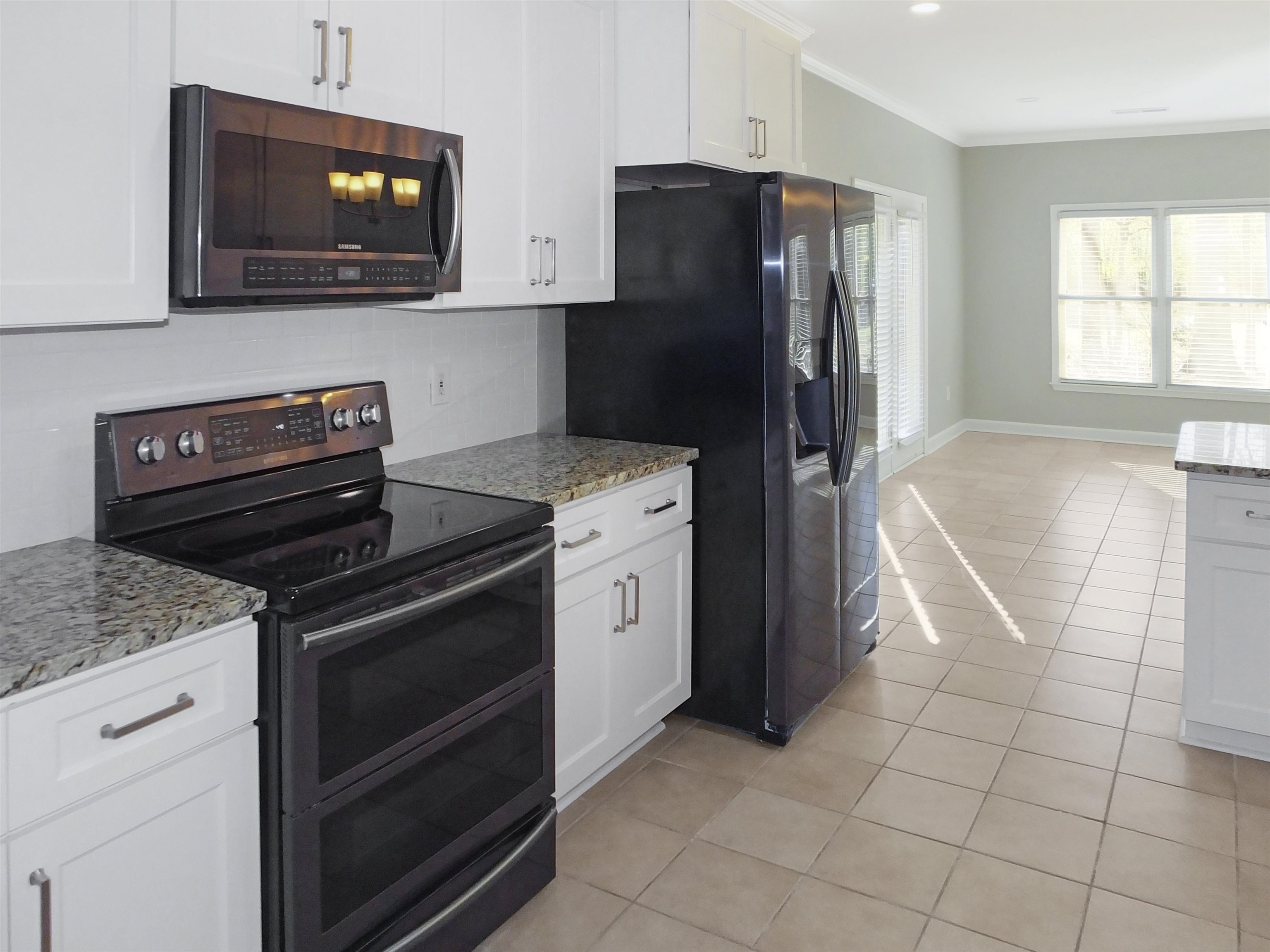 4323 Country Bridge Road Lakeland, TN 38002 - Photo 13 of 35 Kitchen with tasteful backsplash, crown molding, light tile patterned floors, appliances with stainless steel finishes, and white cabinets