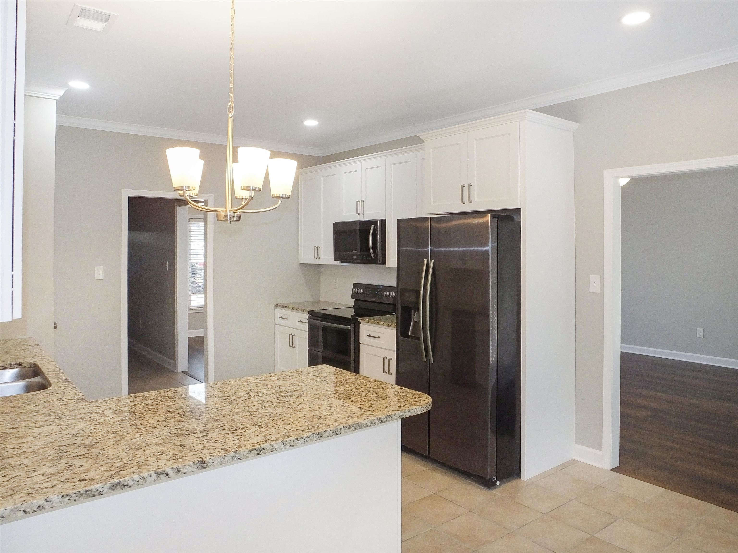 4323 Country Bridge Road Lakeland, TN 38002 - Photo 16 of 35 Kitchen featuring crown molding, black range with electric cooktop, stainless steel fridge with ice dispenser, a chandelier, and white cabinets