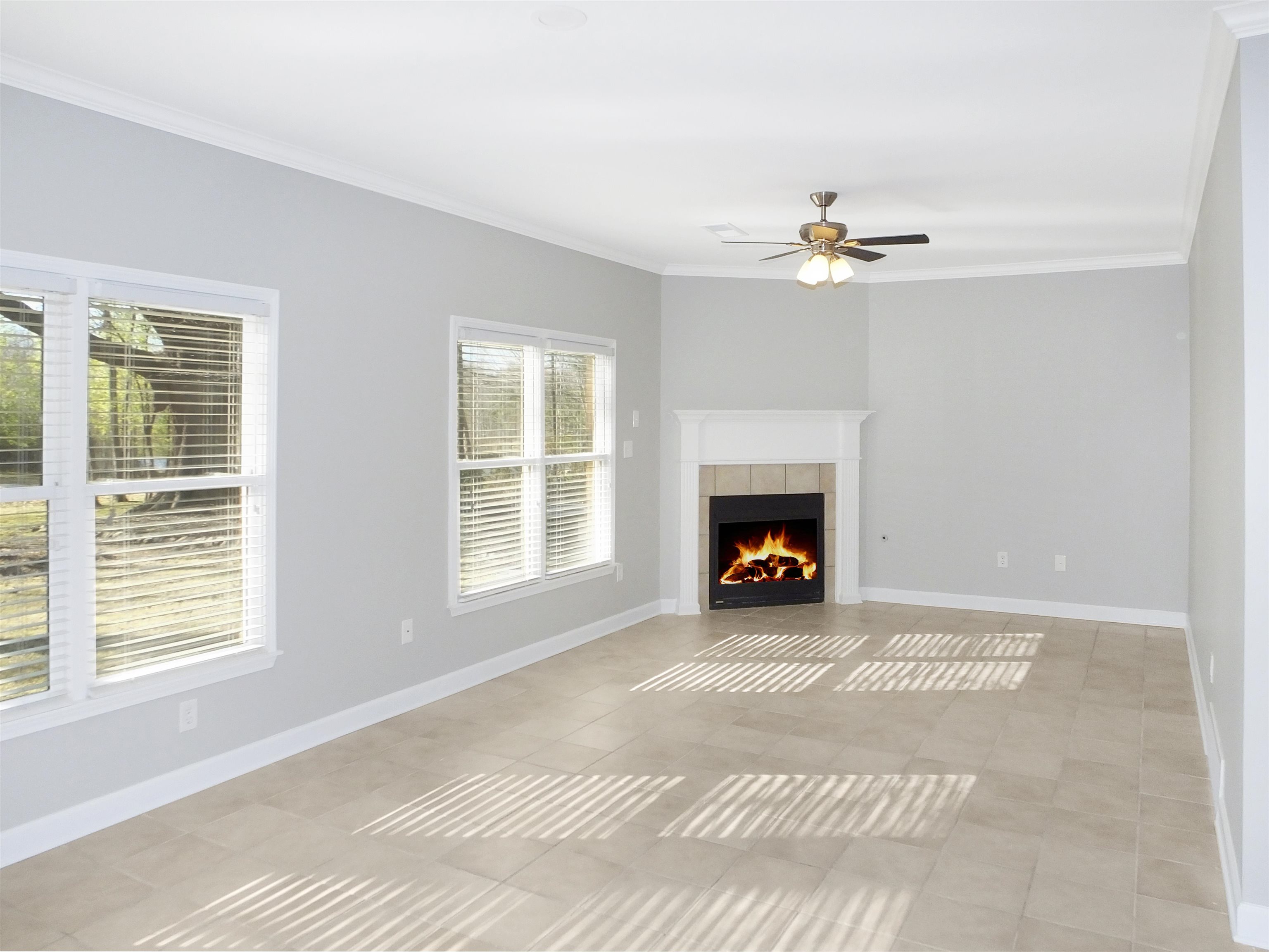 4323 Country Bridge Road Lakeland, TN 38002 - Photo 18 of 35 Unfurnished living room featuring baseboards, ornamental molding, light tile patterned floors, a tile fireplace, and a ceiling fan