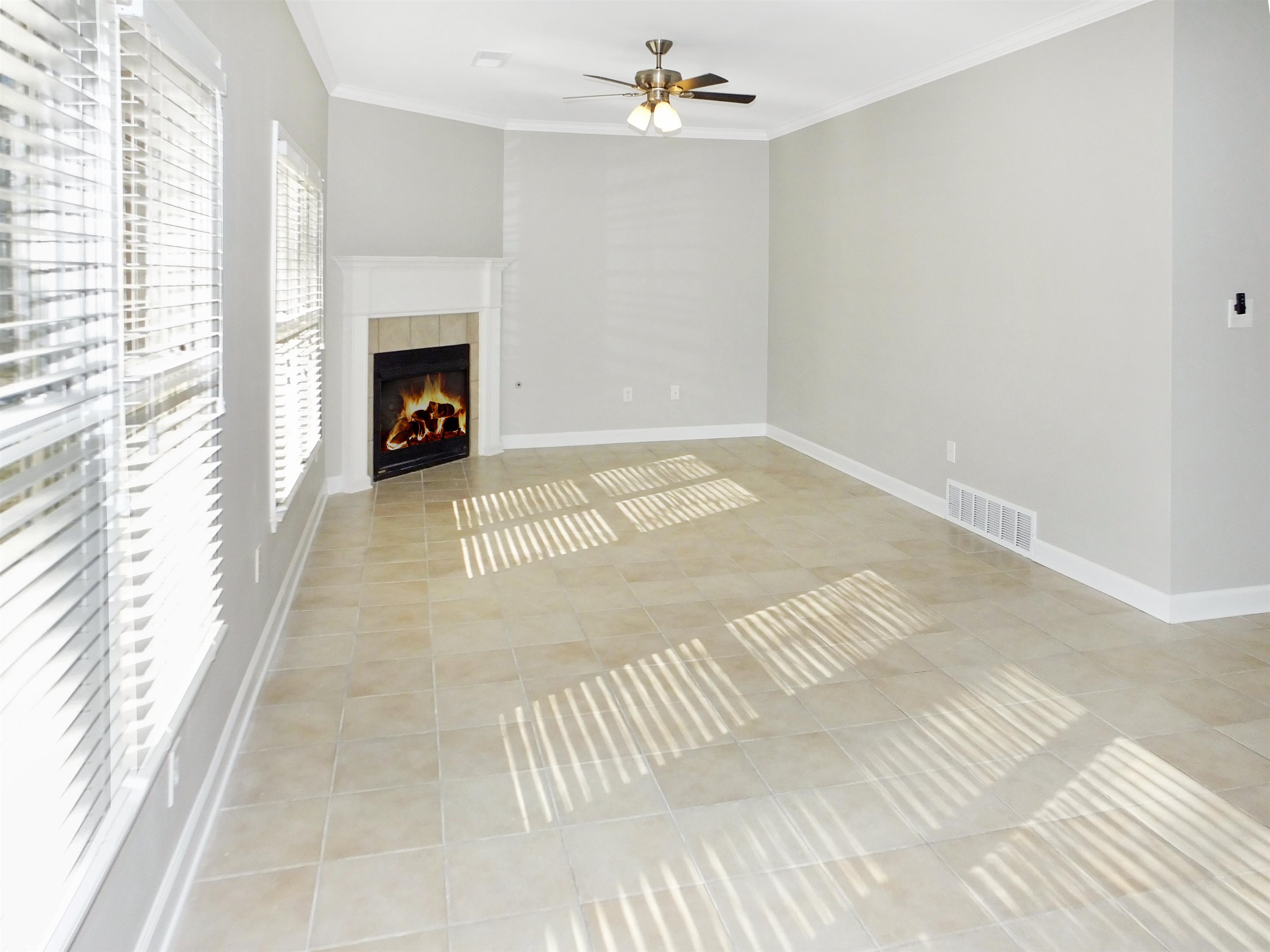 4323 Country Bridge Road Lakeland, TN 38002 - Photo 20 of 35 Unfurnished living room featuring visible vents, crown molding, a tiled fireplace, light tile patterned floors, and a ceiling fan