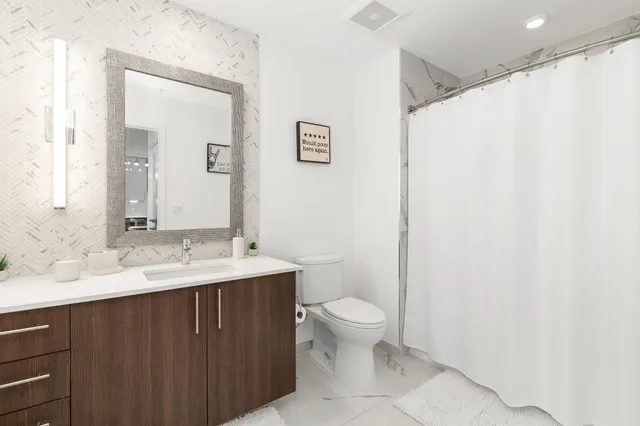 a bathroom with a granite countertop sink a toilet and a mirror