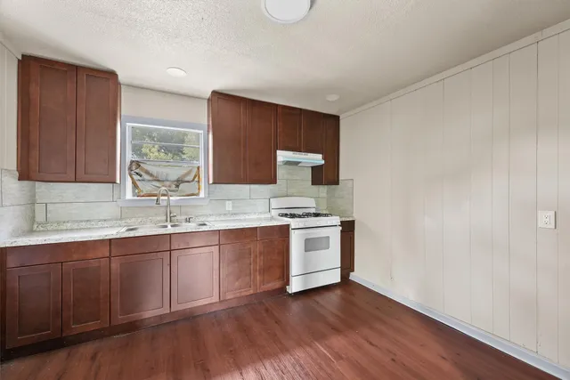 a kitchen with granite countertop a sink cabinets and wooden floor