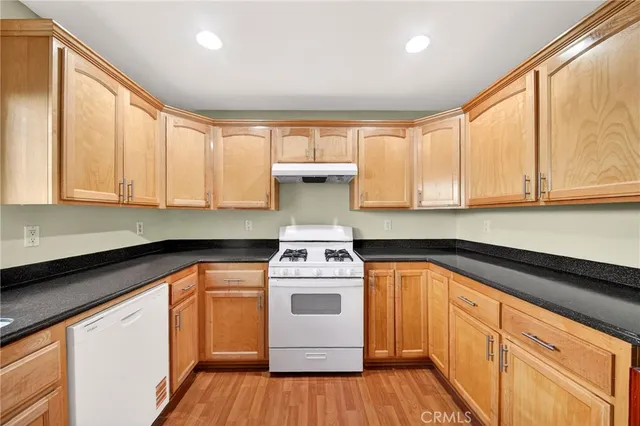 a kitchen with a stove a sink and wooden floor