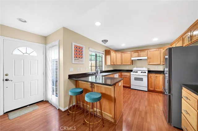 a open kitchen with stainless steel appliances granite countertop a refrigerator a stove top oven and a dining table with wooden floor