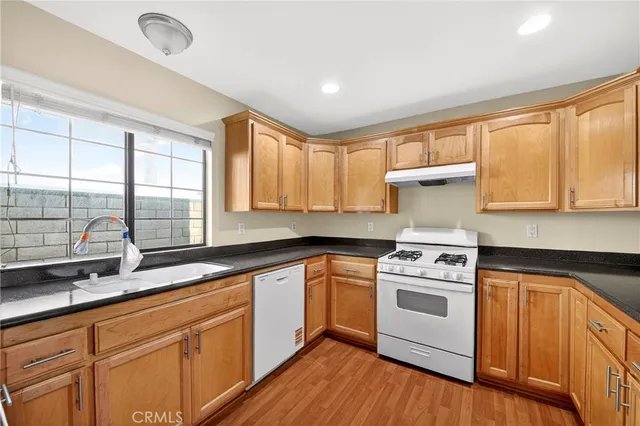 a kitchen with a stove a sink and wooden cabinets