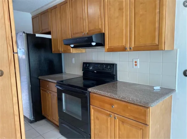 a kitchen with stainless steel appliances granite countertop a stove a refrigerator and a sink with wooden cabinets