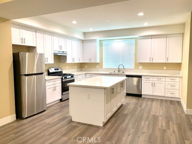 a kitchen with a refrigerator a sink dishwasher with a oven and cabinets