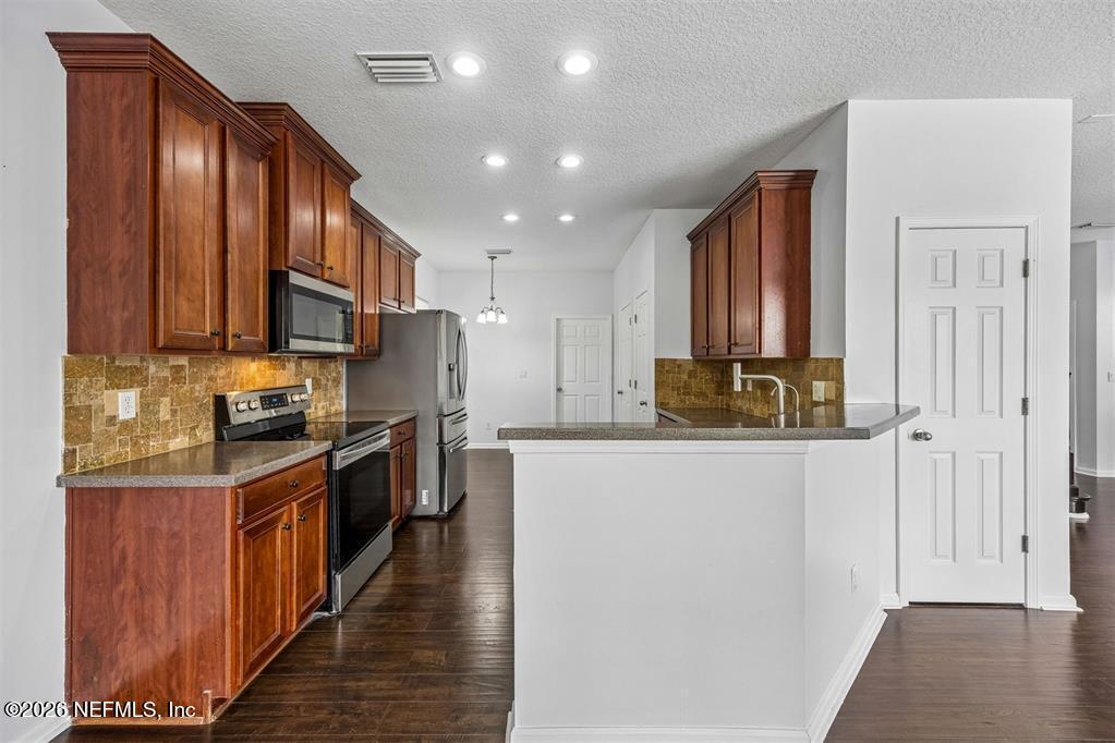 96204 Coral Reef Road Yulee, FL 32097 - Photo 13 of 40 a kitchen with stainless steel appliances granite countertop a refrigerator a stove top oven a sink and dishwasher