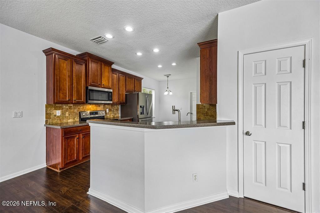 96204 Coral Reef Road Yulee, FL 32097 - Photo 14 of 40 a kitchen with stainless steel appliances granite countertop a refrigerator a stove top oven a sink and dishwasher