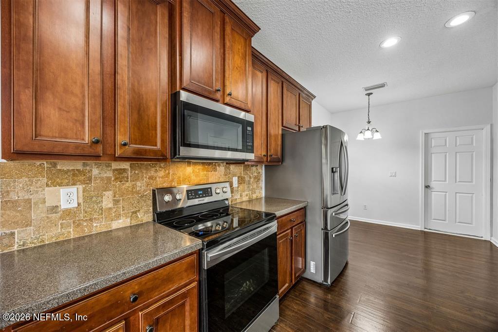 96204 Coral Reef Road Yulee, FL 32097 - Photo 15 of 40 a kitchen with stainless steel appliances granite countertop a refrigerator stove and microwave