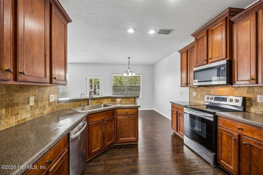 96204 Coral Reef Road Yulee, FL 32097 - Photo 2 of 40 a kitchen with stainless steel appliances granite countertop a sink a stove and cabinets