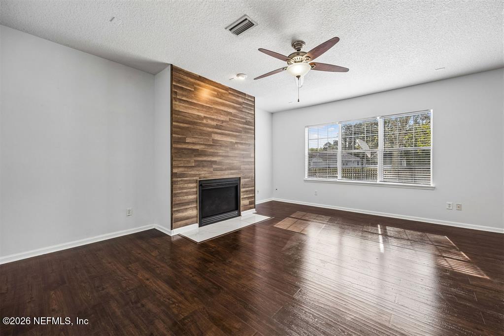 96204 Coral Reef Road Yulee, FL 32097 - Photo 3 of 40 an empty room with wooden floor fireplace and windows