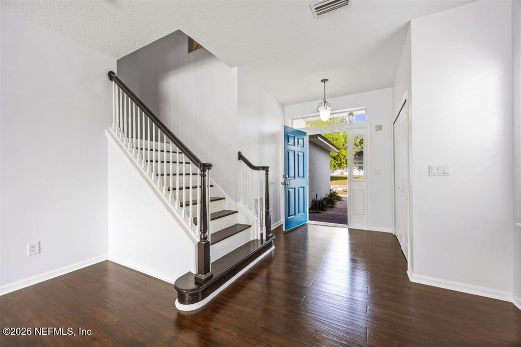 96204 Coral Reef Road Yulee, FL 32097 - Photo 7 of 40 a view of a hallway with wooden floor and staircase