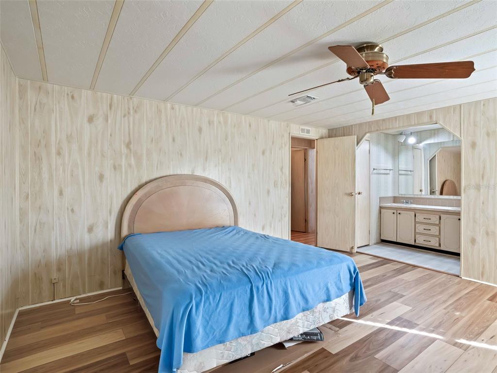 1102 Dustin Drive The Villages, FL 32159 - Photo 21 of 38 a bedroom with a bed a mirror and a ceiling fan