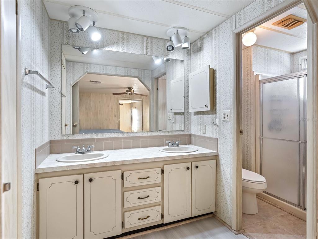 1102 Dustin Drive The Villages, FL 32159 - Photo 22 of 38 a spacious bathroom with a double vanity sink a large mirror a toilet and a shower