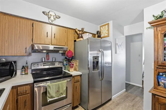 a kitchen with stainless steel appliances granite countertop a refrigerator a stove and a sink with wooden floor