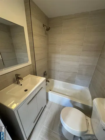a bathroom with a tub toilet sink mirror and vanity