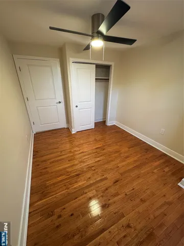 an empty room with wooden floor and fan
