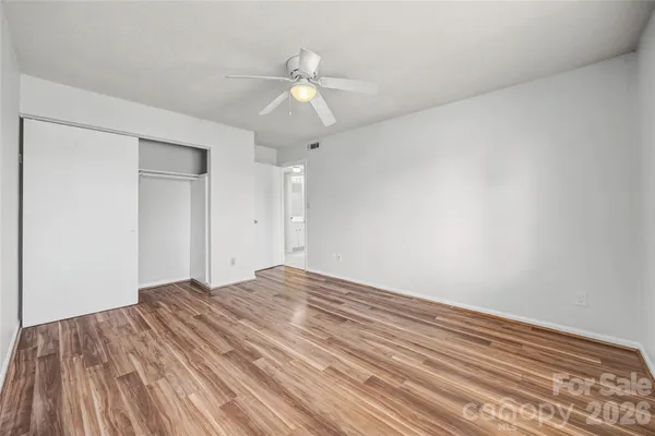 a view of empty room with wooden floor and ceiling fan