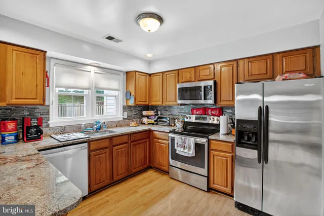 a kitchen with granite countertop a sink stainless steel appliances and cabinets