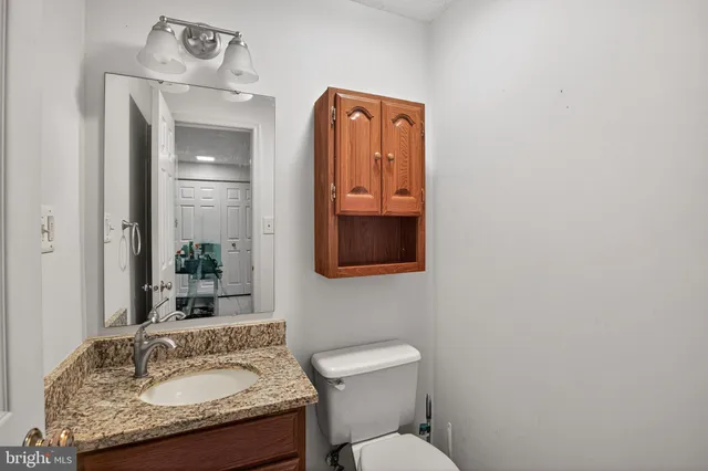 a bathroom with a granite countertop toilet sink and mirror