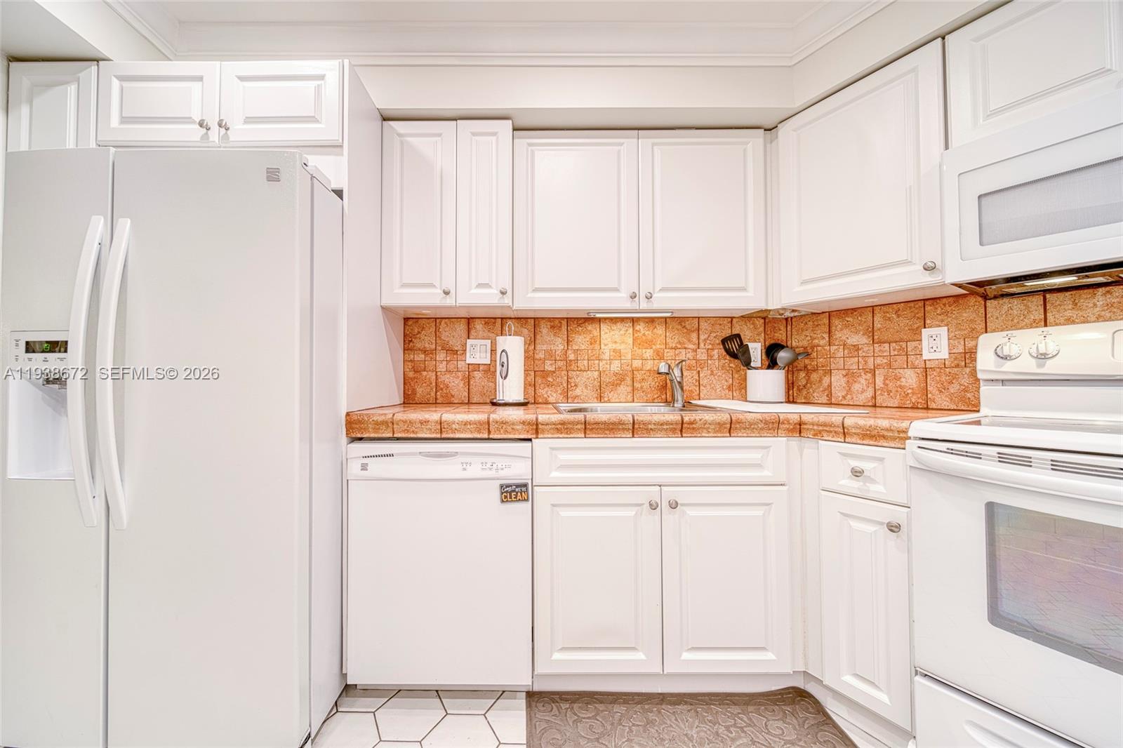 1111 Crandon Boulevard, Unit C404 Key Biscayne, FL 33149 - Photo 13 of 44 a kitchen with white cabinets and white appliances