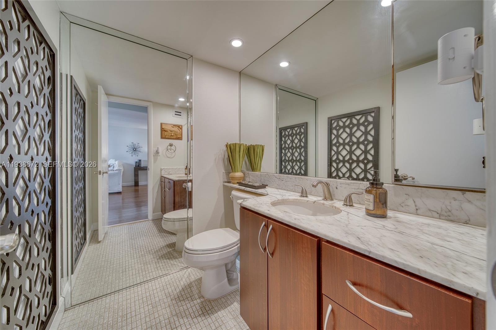 1111 Crandon Boulevard, Unit C404 Key Biscayne, FL 33149 - Photo 15 of 44 a bathroom with a granite countertop sink a toilet a mirror and shower