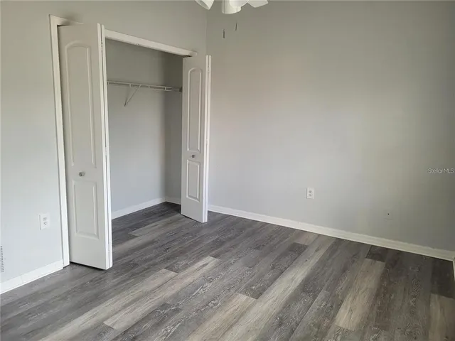 a view of an empty room with wooden floor and closet