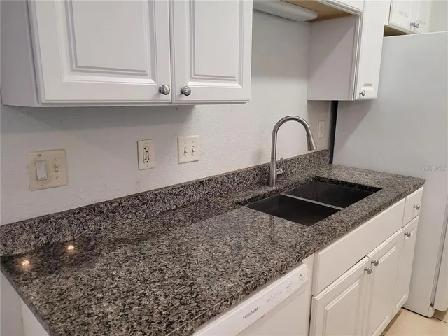 a kitchen with granite countertop white cabinets and a sink