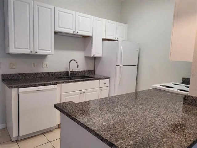 a kitchen with granite countertop a sink stove and refrigerator