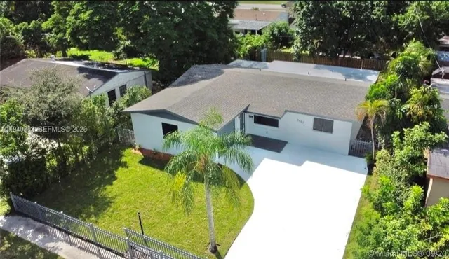 an aerial view of a house with swimming pool and large trees