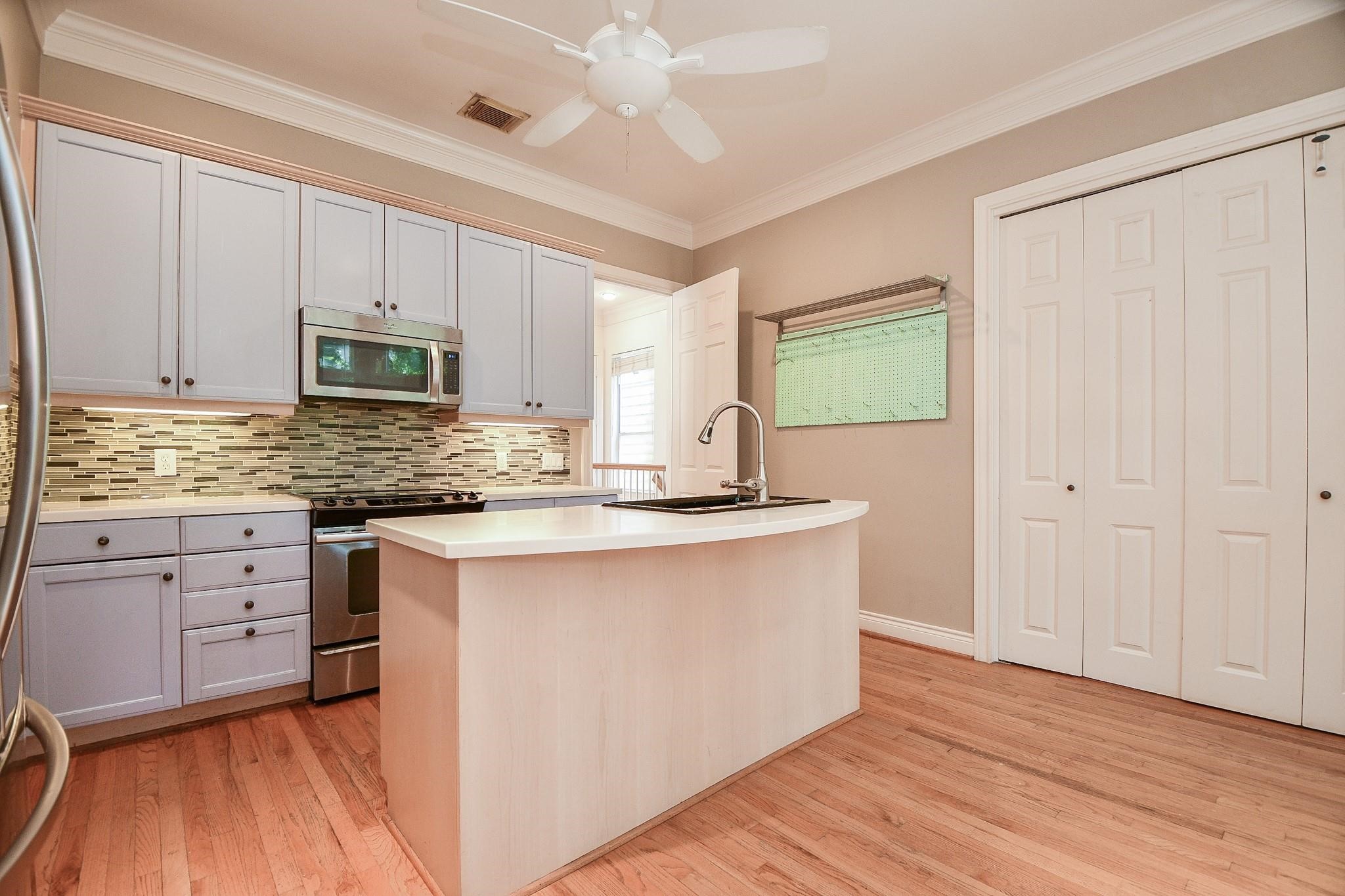 1025 Marconi Street Houston, TX 77019 - Photo 6 of 19 a kitchen with kitchen island granite countertop wooden cabinets and white appliances