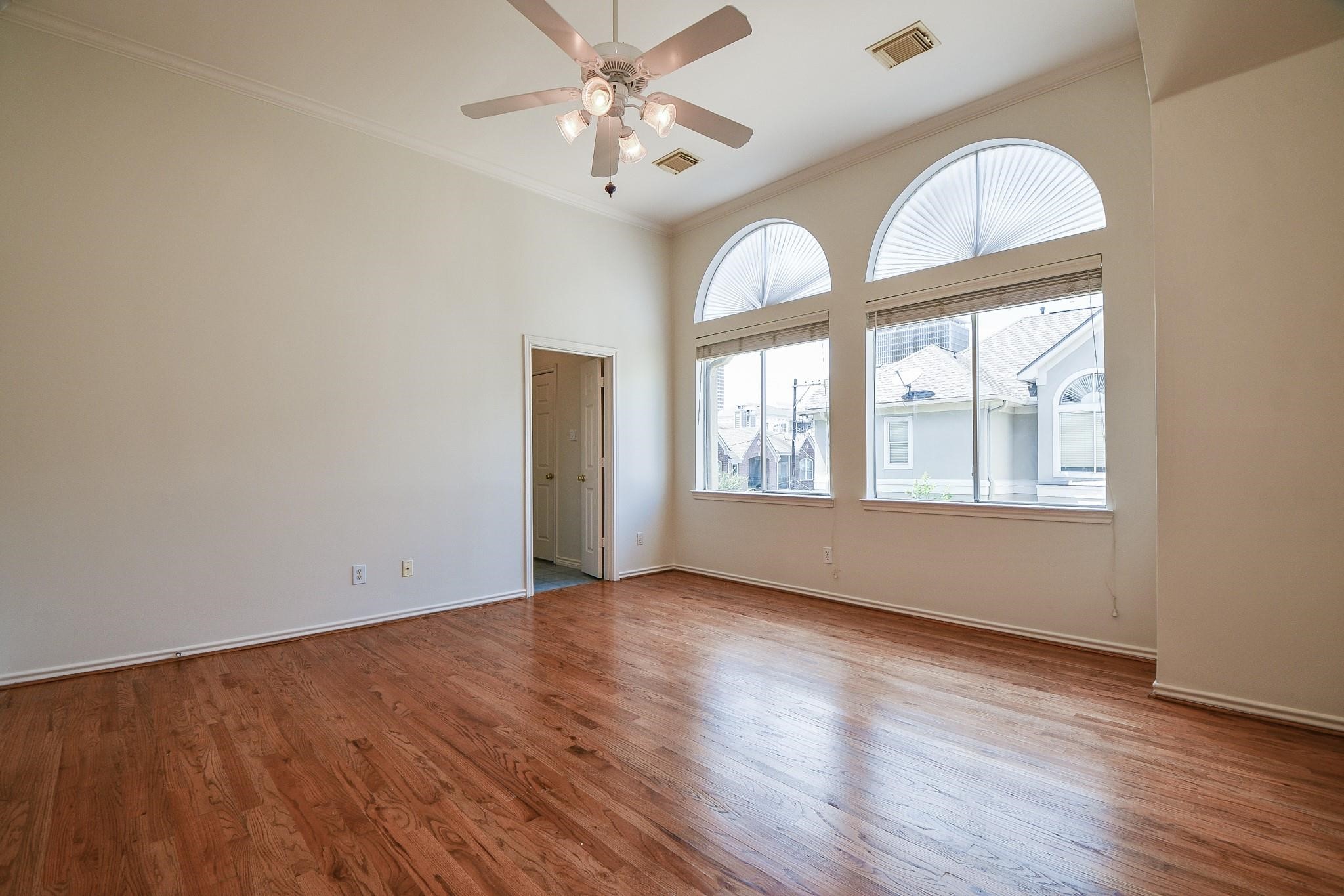 1025 Marconi Street Houston, TX 77019 - Photo 9 of 19 an empty room with wooden floor chandelier fan and windows