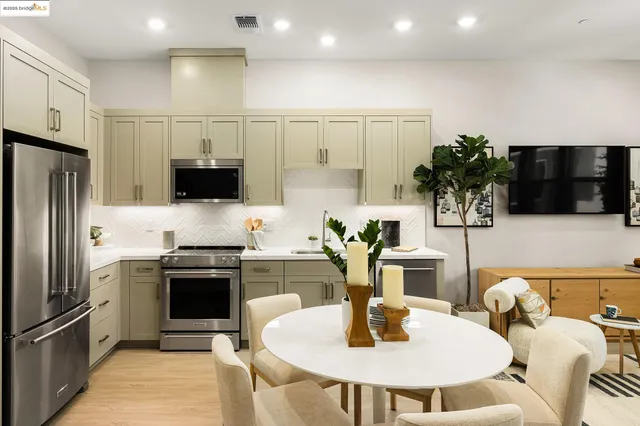 a kitchen with stainless steel appliances granite countertop a sink a stove a microwave a refrigerator and chairs