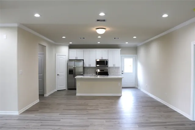 a large kitchen with stainless steel appliances kitchen island a sink dishwasher a refrigerator and a stove with wooden floor