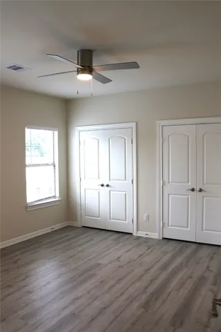 an empty room with wooden floor cabinet and windows