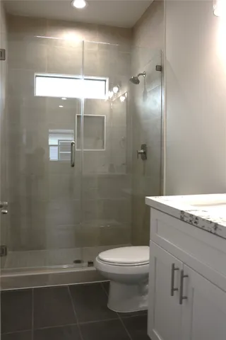 a bathroom with a granite countertop shower a toilet and a shower