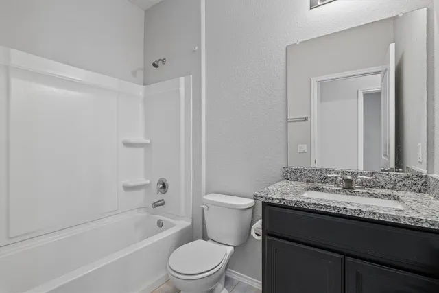 a bathroom with a granite countertop sink a toilet and shower
