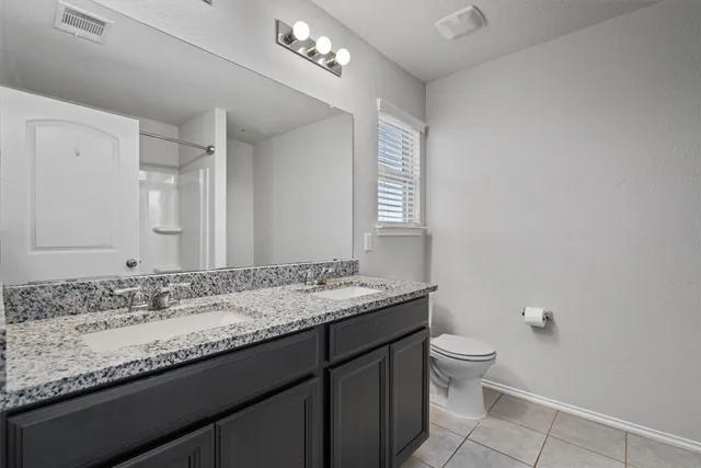 a bathroom with a granite countertop sink a toilet and a mirror