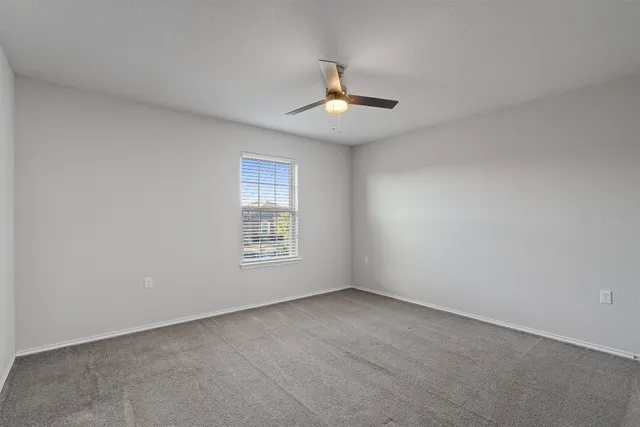 an empty room with a window and ceiling fan