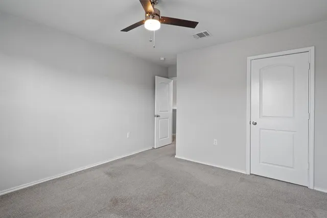 an empty room with a ceiling fan and a window
