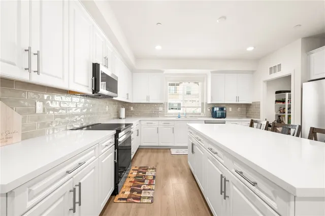 a kitchen with stainless steel appliances granite countertop white cabinets a sink and dishwasher
