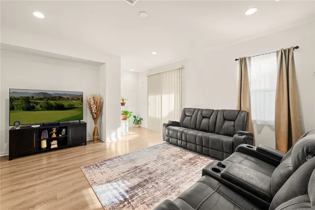 a living room with furniture and kitchen view with wooden floor