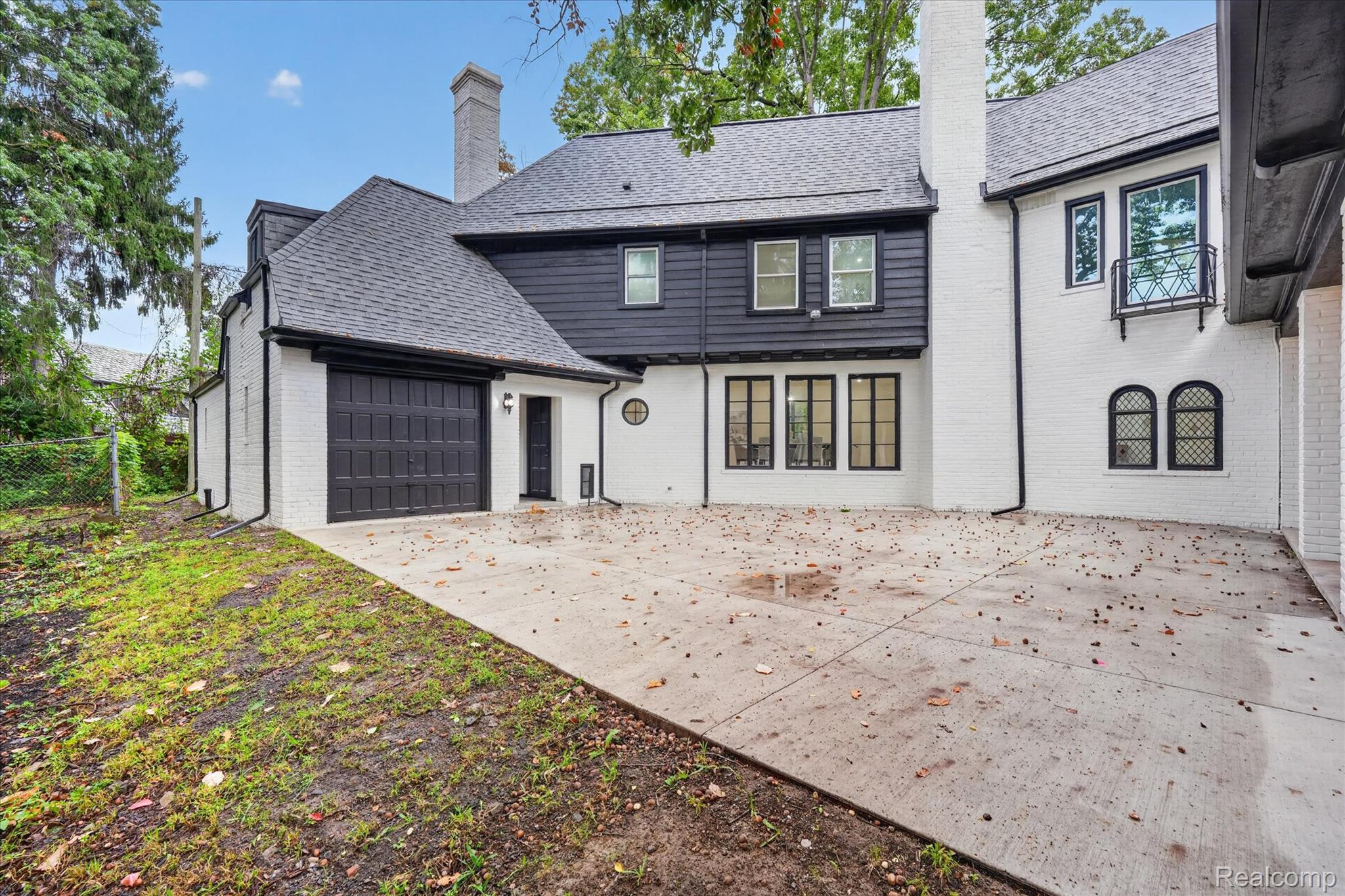3250 Sherbourne Road Detroit, MI 48221 - Photo 35 of 36 Exterior featuring white brick, dark horizontal siding, a dark asphalt shingle roof, a black garage door, and multiple windows with dark frames