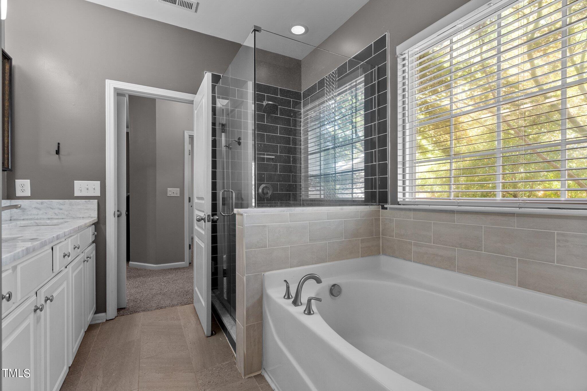 5016 Paperbark Court Durham, NC 27713 - Photo 14 of 35 a bathroom with a granite countertop tub sink a window and a shower