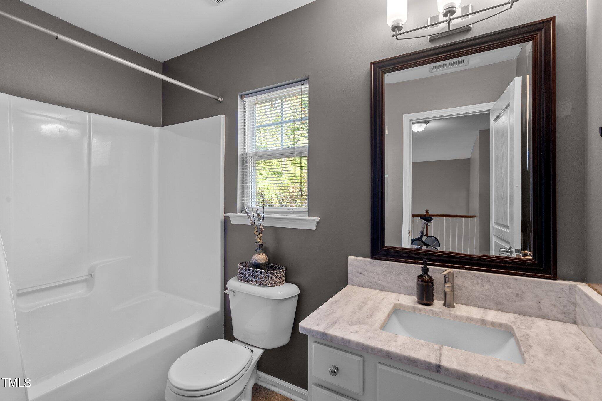 5016 Paperbark Court Durham, NC 27713 - Photo 19 of 35 a bathroom with a granite countertop sink toilet a mirror and bathtub