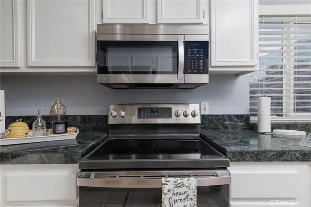 a kitchen with granite countertop a stove and a white cabinets