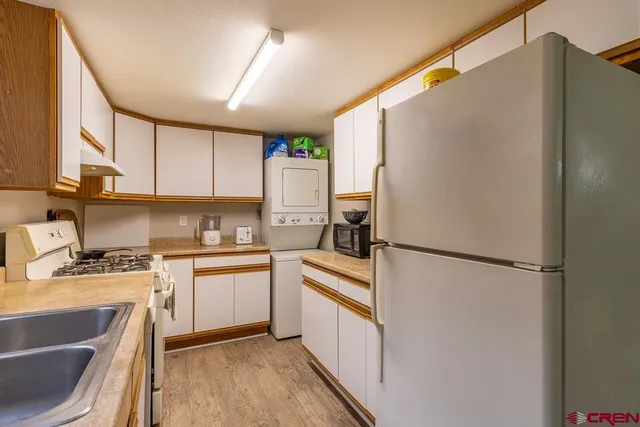 a kitchen with a refrigerator a stove a sink dishwasher and white cabinets with wooden floor