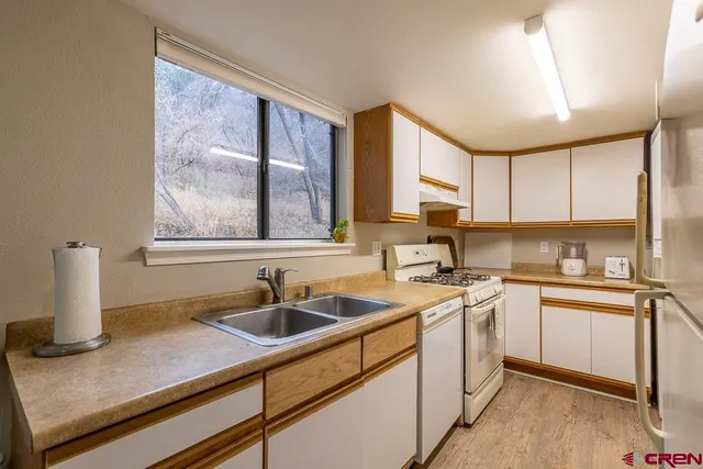 a kitchen with a sink cabinets stainless steel appliances and a window