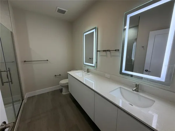 a bathroom with a granite countertop sink a toilet and mirror
